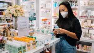 Mulher asiática, de blusa preta e short jeans conferindo embalagens de produtos em uma farmácias no Buritis
