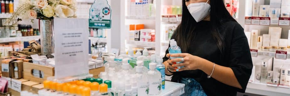 Mulher asiática, de blusa preta e short jeans conferindo embalagens de produtos em uma farmácias no Buritis