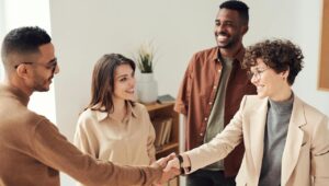 4 pessoas dando as mãos e finalizando um negócio com a presença de um interveniente anuente