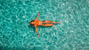Mulher de biquini laranja boiando em uma grande piscina para ilustrar o artigo Clubes em BH
