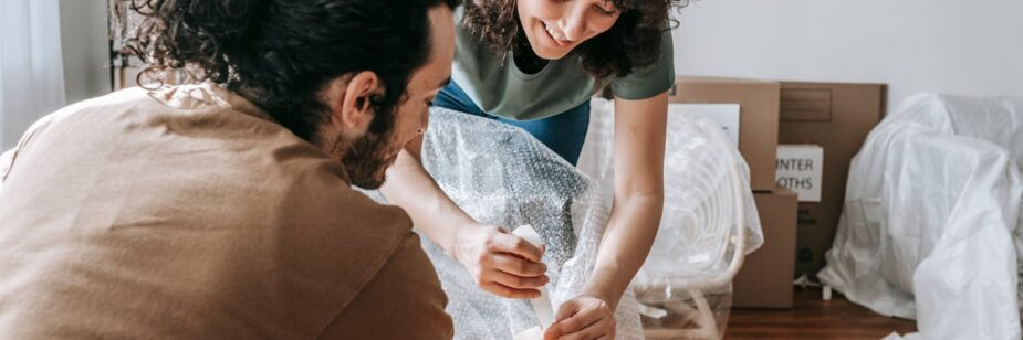 Um casal se preparando para mudar de cidade, colocando suas coisas em caixas