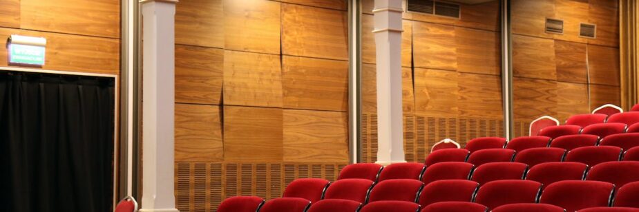 Salas de cinemas em BH com várias cadeiras vermelhas e uma parede amadeirada ao fundo