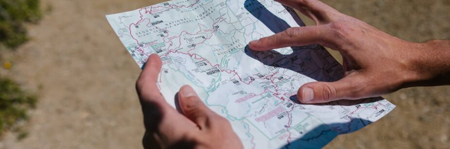 Duas mãos segurando um mapa pequeno para se localizar, ilustrando o artigo trilhas em BH