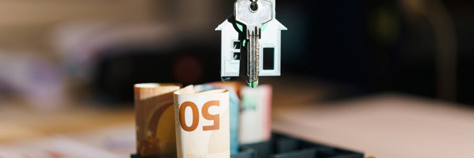 Um chaveiro de casa com uma chave pendurados acima de notas de dinheiro para exemplificar o que é um correspondente bancário