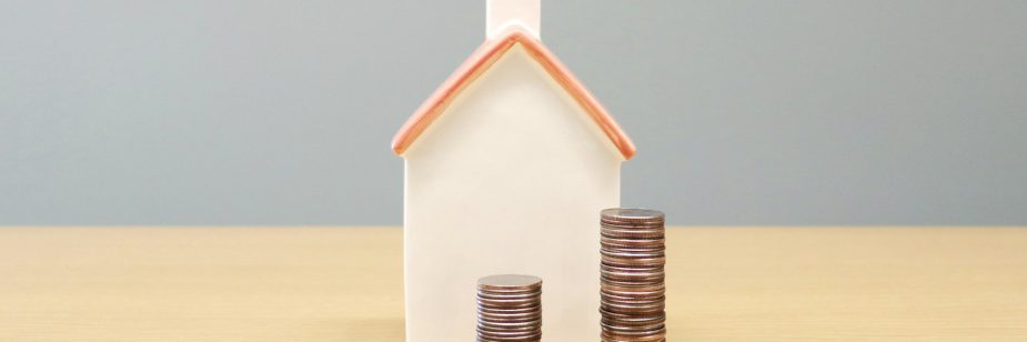 Casa em miniatura ao fundo com três pilhas de moedas em crescimento à frente, representando valorização e investimento em fundos imobiliários.